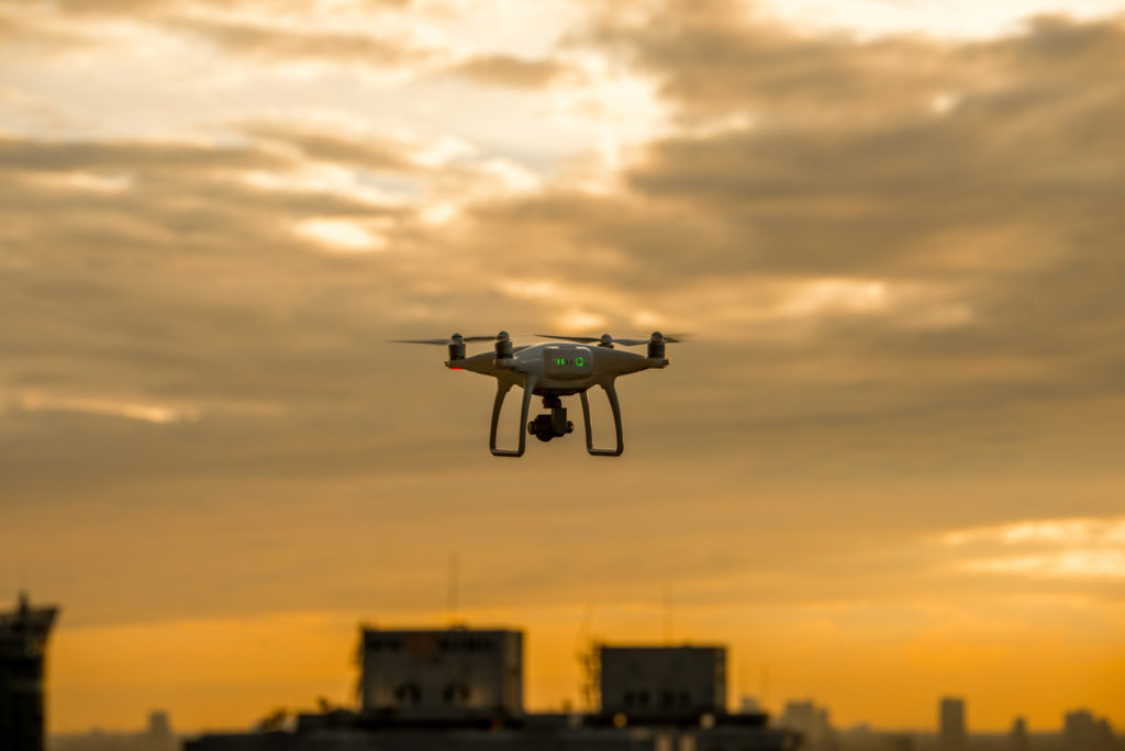Image shows a single drone flying over a city at sunset to answer the question of what is the most advanced drone.
